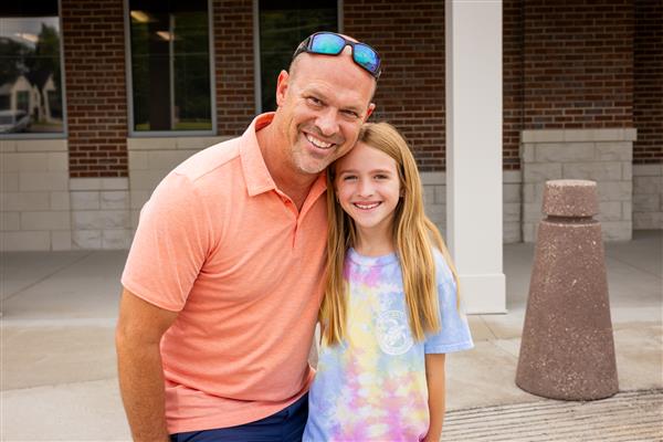 dad and girl smiling with arms around each other